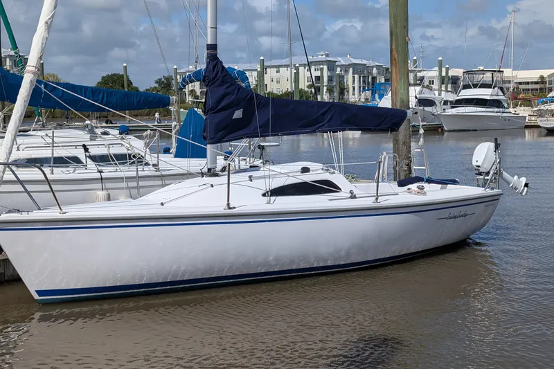 Slide: The Image of 2013 Catalina 22 Capri sailboat docked in a marina, featuring a sleek white hull. - 0