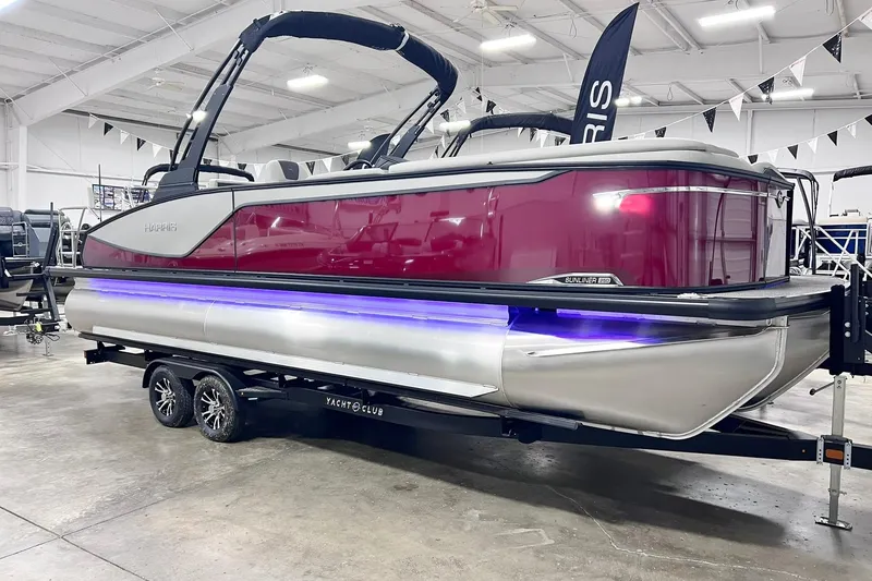 The Image of 2026 Harris Sunliner 250 SLE pontoon boat with vibrant red exterior in showroom. - 0