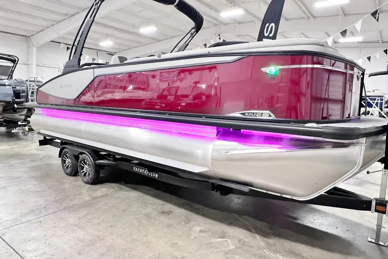 Slide: The Image of 2026 Harris Sunliner 250 SLE pontoon boat with vibrant pink lighting on trailer. - 1