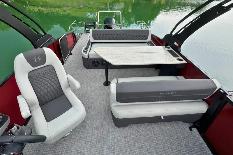 Slide: The Image of 2026 Harris Sunliner 250 SLE pontoon boat interior with seating and table on calm water. - 14