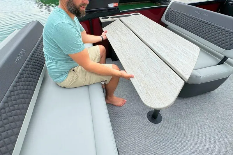 Slide: The Image of Man adjusting table on 2026 Harris Sunliner 250 SLE pontoon boat. - 16