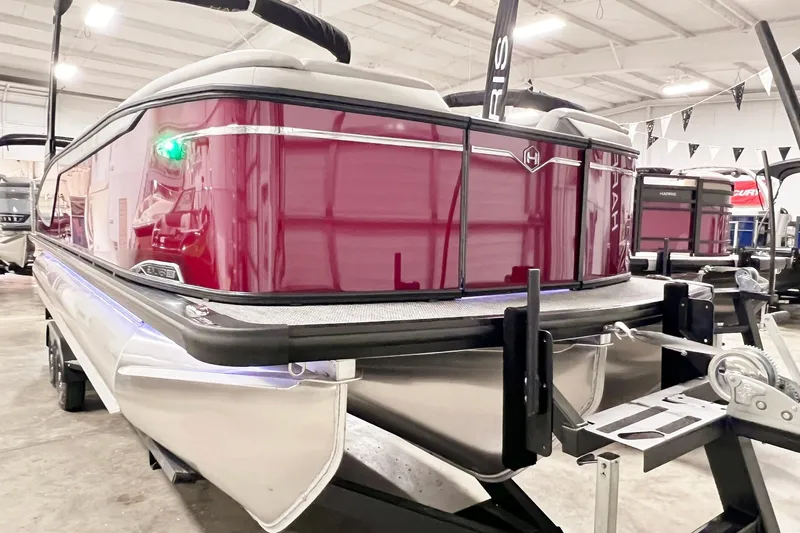 Slide: The Image of 2026 Harris Sunliner 250 SLE pontoon boat in showroom, featuring sleek design and vibrant red exterior. - 4