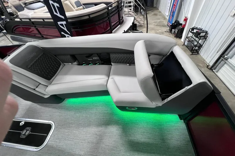 Slide: The Image of 2026 Harris Sunliner 250 SLE boat interior with gray seating and green LED lighting. - 43