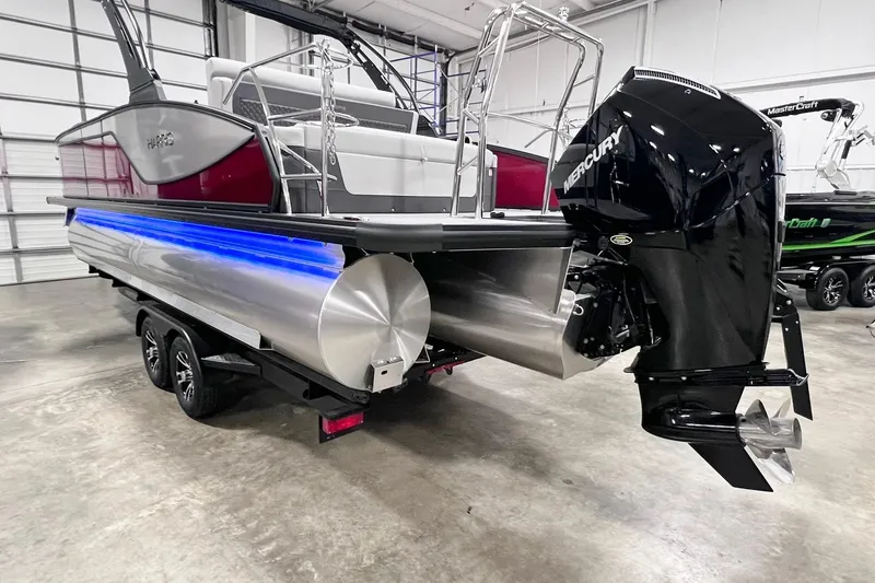 Slide: The Image of 2026 Harris Sunliner 250 SLE pontoon boat with Mercury outboard motor in showroom. - 6