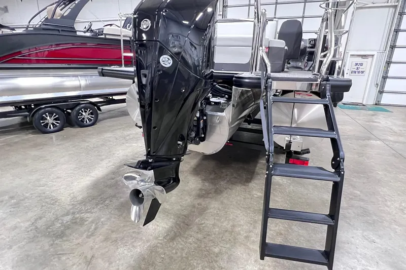 Slide: The Image of 2026 Harris Sunliner 250 SLE pontoon boat with outboard motor and boarding ladder in a showroom. - 61