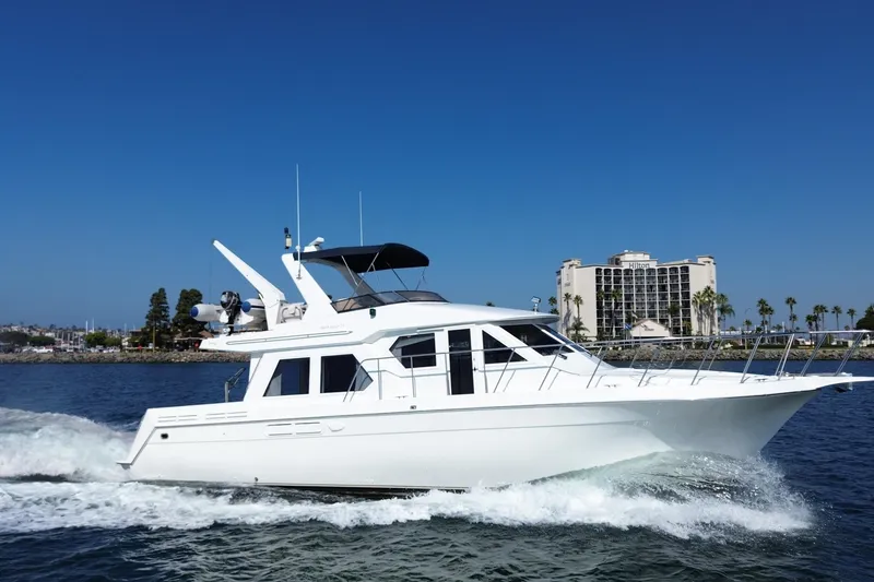 Slide: The Image of 1998 Navigator 4800 yacht cruising on water near a hotel and palm trees. - 2