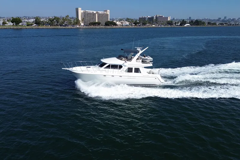 Slide: The Image of 1998 Navigator 4800 yacht cruising on a sunny day near a coastal cityscape. - 3