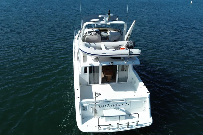 Slide: The Image of 1998 Navigator 4800 yacht on calm blue water, rear view with upper deck. - 5
