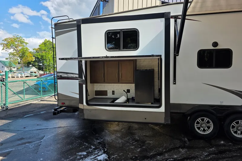 Slide: The Image of 2018 Heritage Glen 356QB RV with outdoor kitchen setup, featuring cabinets and a mini fridge. - 12