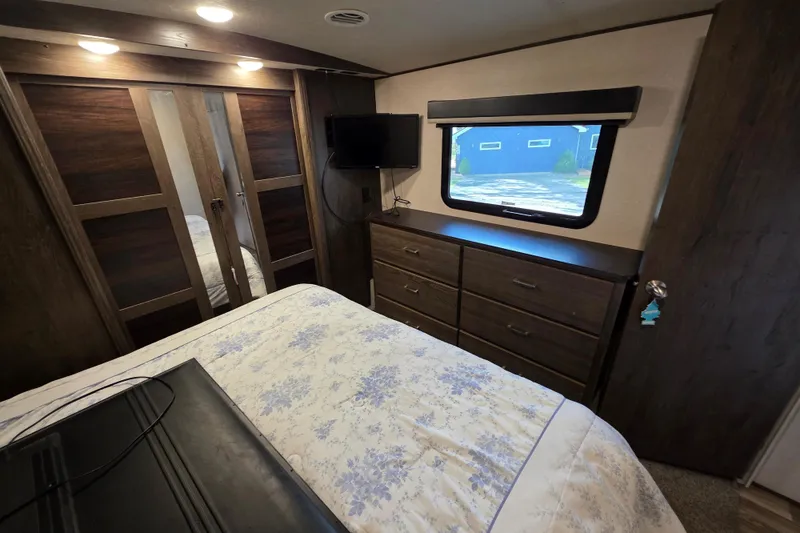 Slide: The Image of 2018 Heritage Glen 356QB bedroom interior with bed, dresser, TV, and window view. - 15