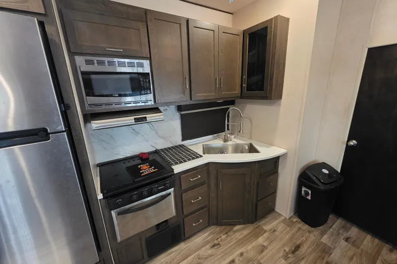 Slide: The Image of 2018 Heritage Glen 356QB kitchen with stainless appliances, wood cabinets, and modern fixtures. - 19