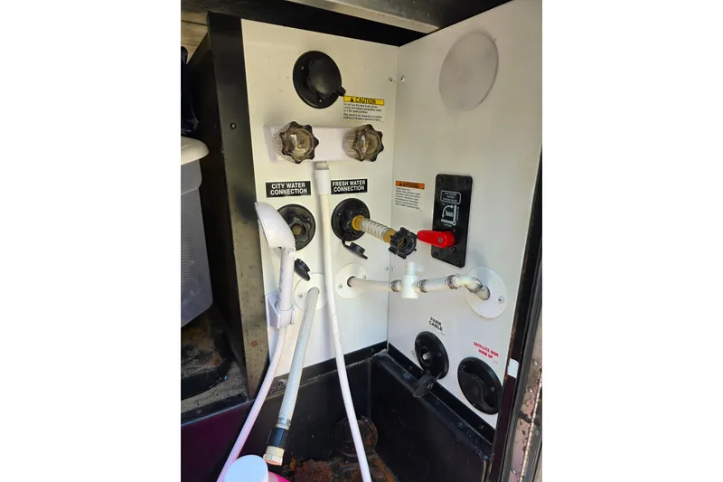 Slide: The Image of 2018 Heritage Glen 356QB RV water connections panel with hoses and controls. - 34