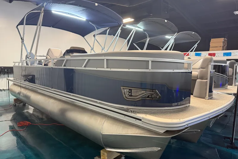 Slide: The Image of 2026 Tahoe Pontoon Sport 85 Rear Fish boat with blue canopy in showroom. - 1