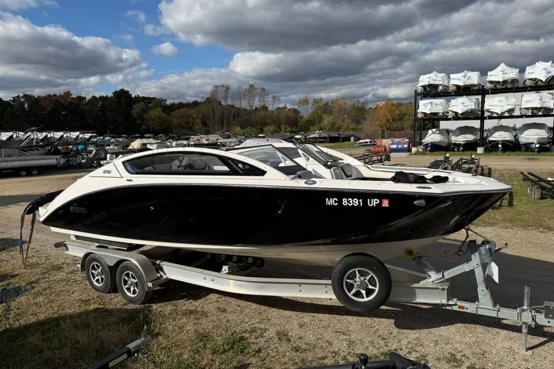 Slide: The Image of 2021 Yamaha Boats 275 E on trailer, parked outdoors under cloudy sky. - 0