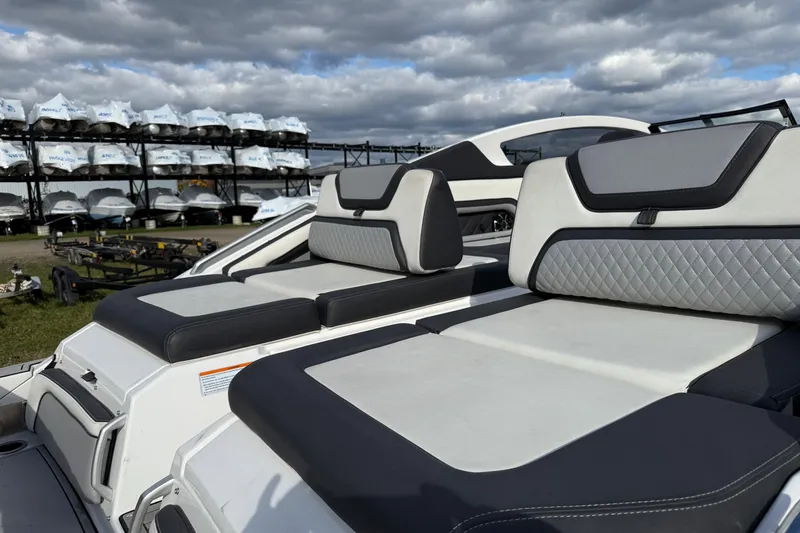 Slide: The Image of 2021 Yamaha Boats 275 E with luxurious seating, stored outdoors under cloudy skies. - 12