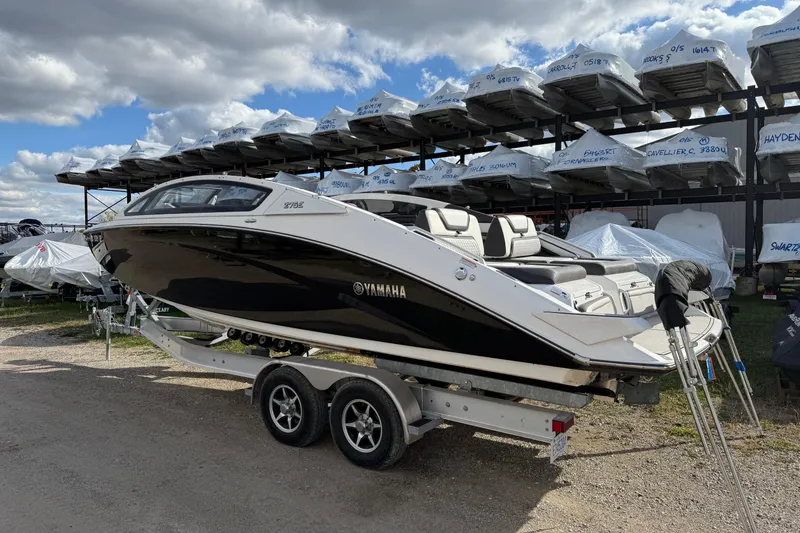 Slide: The Image of 2021 Yamaha Boats 275 E on trailer, parked outdoors under cloudy sky. - 2