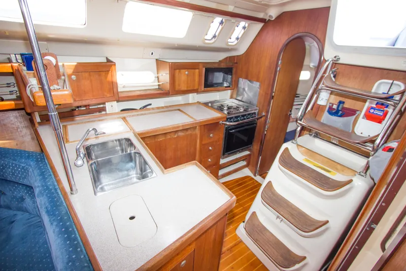 Slide: The Image of Interior of 1997 Hunter 376 sailboat featuring kitchen with sink, stove, and wooden cabinetry. - 11