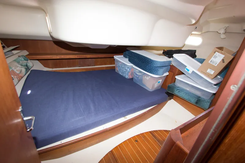Slide: The Image of Cabin interior of 1997 Hunter 376 sailboat with storage containers and blue mattress. - 13