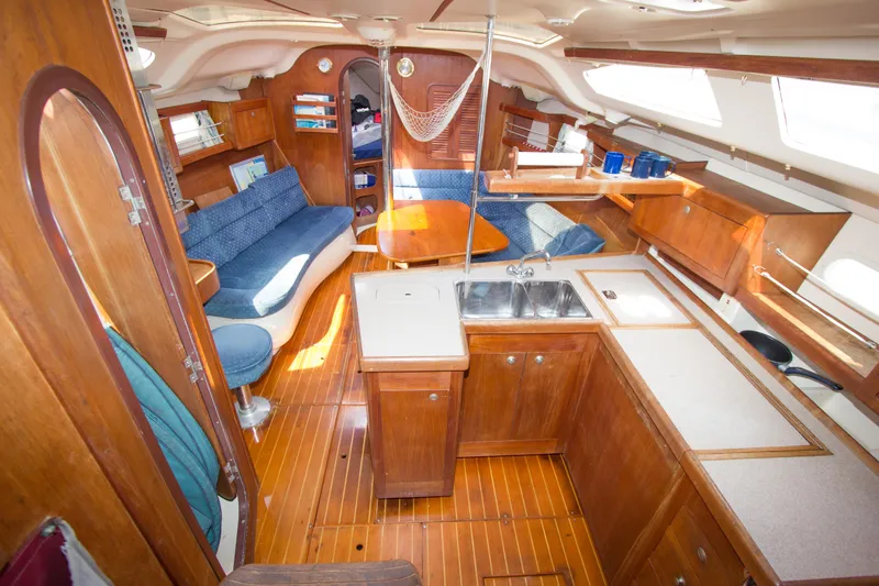 Slide: The Image of Interior of a 1997 Hunter 376 sailboat with wooden cabinetry and blue seating. - 2