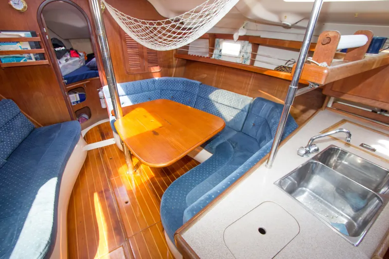 Slide: The Image of Interior of a 1997 Hunter 376 sailboat with wooden table and blue seating. - 5