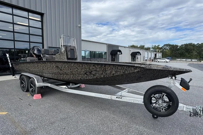 The Image of 2026 Xpress H22B Bay boat on trailer, parked outside industrial building. - 1