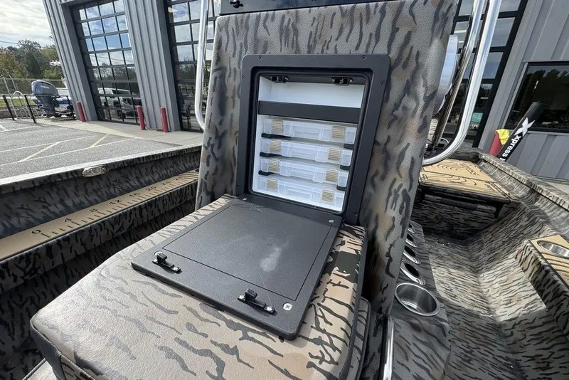 Slide: The Image of 2026 Xpress H22B Bay boat with open storage compartment, camo design, and outdoor setting. - 15