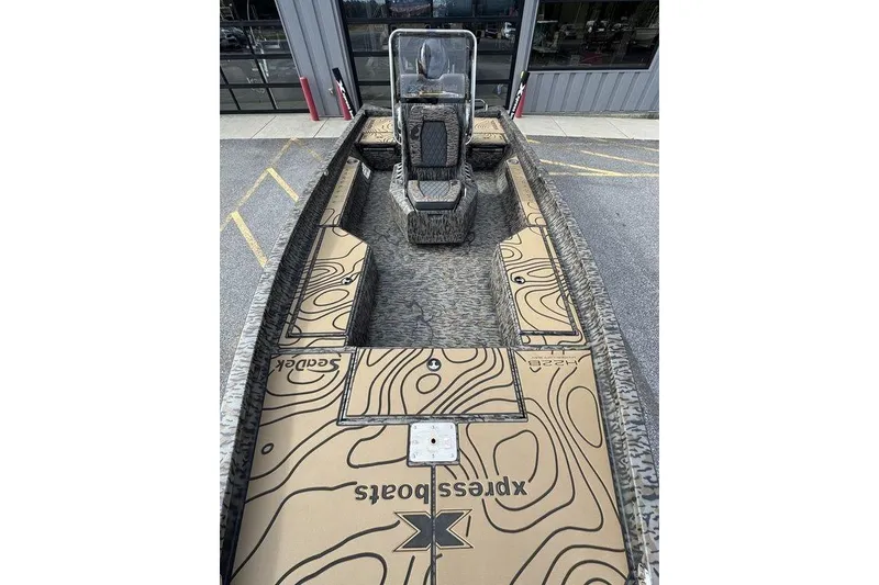 Slide: The Image of 2026 Xpress H22B Bay boat with custom deck design, parked outside a building. - 22