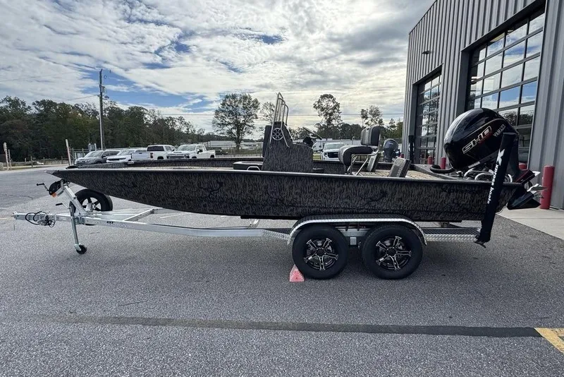 Slide: The Image of 2026 Xpress H22B Bay boat on trailer, parked outside a building under a cloudy sky. - 7