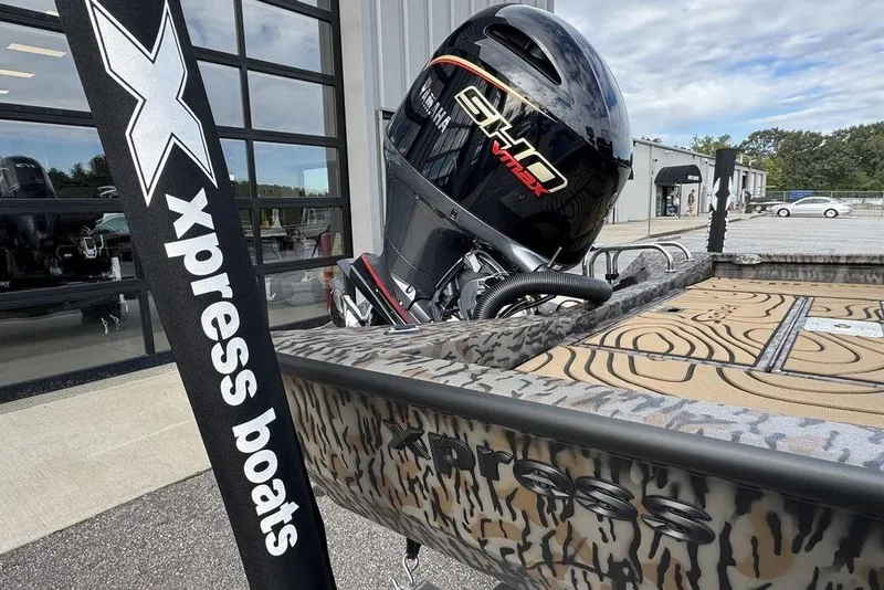 Slide: The Image of 2026 Xpress H22B Bay boat with camo design and powerful outboard motor. - 8