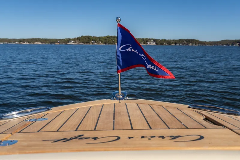 Slide: The Image of 2026 Chris-Craft Sportster 28 boat with flag on calm lake. - 10