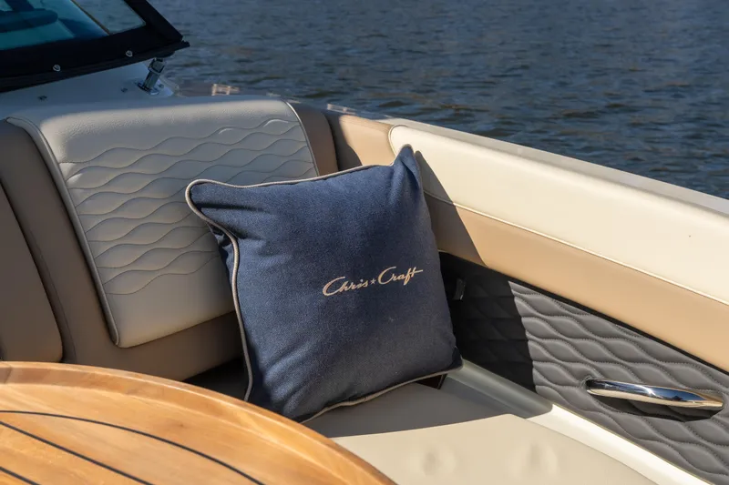 Slide: The Image of 2026 Chris-Craft Sportster 28 interior with logo pillow, elegant seating, and wooden table. - 12