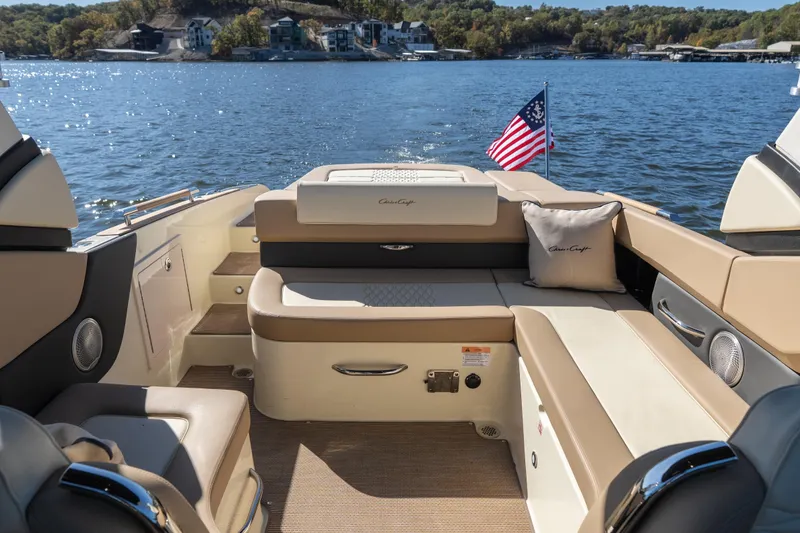 Slide: The Image of 2026 Chris-Craft Sportster 28 boat interior with seating, American flag, and scenic lake view. - 13