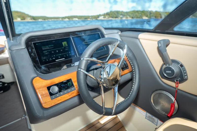 Slide: The Image of 2026 Chris-Craft Sportster 28 dashboard with modern controls and steering wheel on a lake. - 22