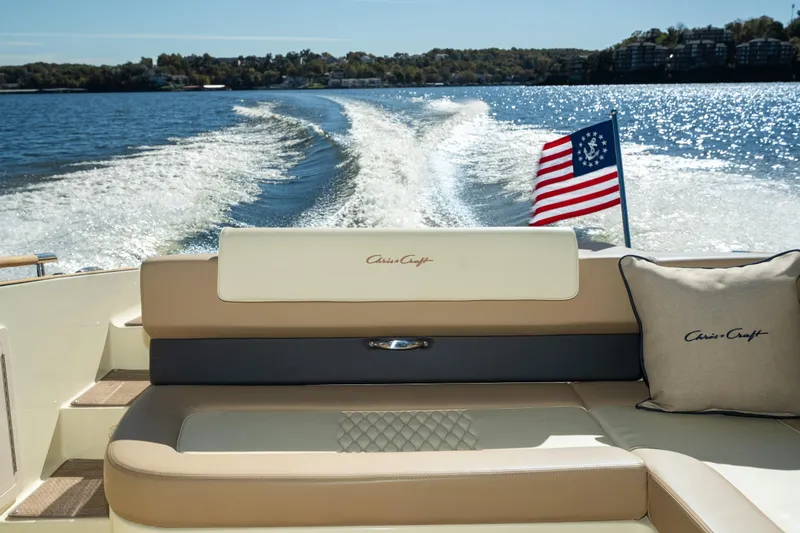 Slide: The Image of 2026 Chris-Craft Sportster 28 boat interior with American flag on a sunny lake. - 30