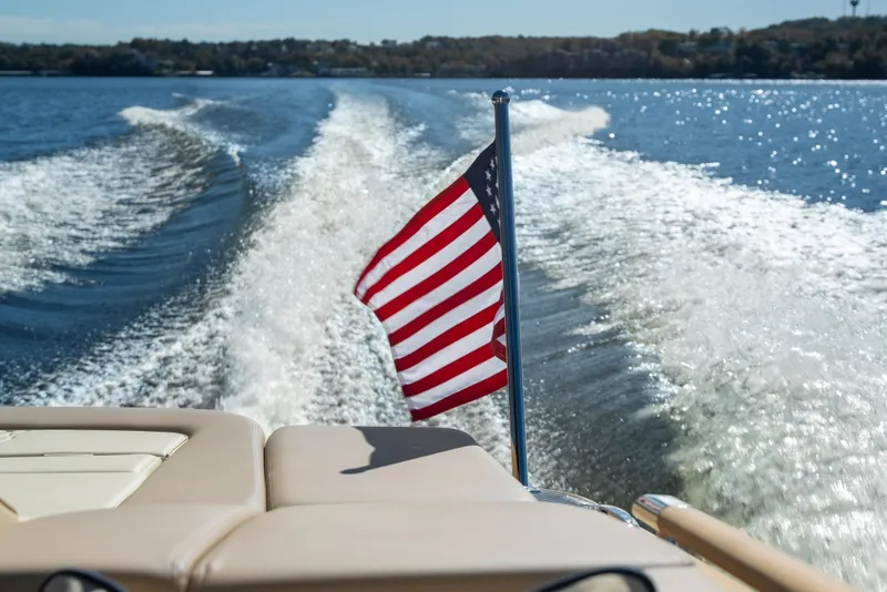 Slide: The Image of 2026 Chris-Craft Sportster 28 cruising with American flag on lake. - 31