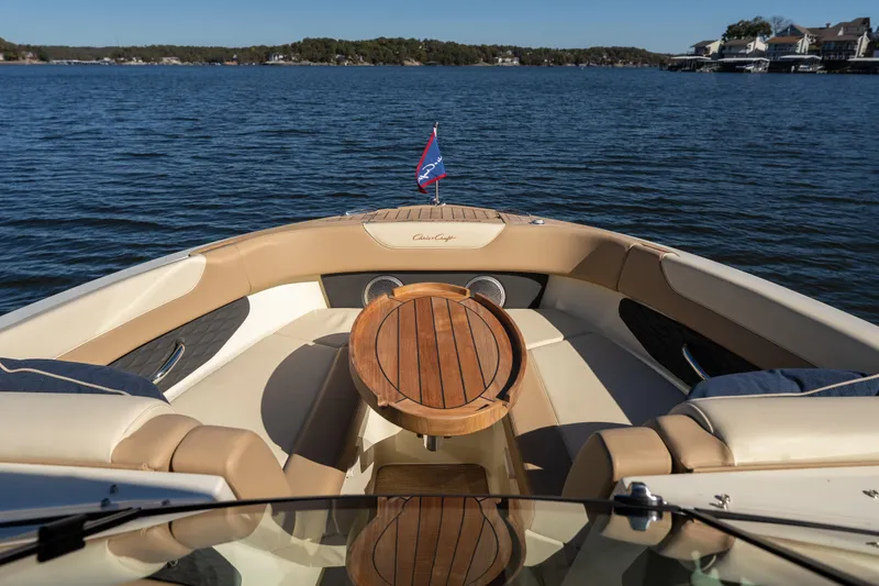 Slide: The Image of 2026 Chris-Craft Sportster 28 boat interior with wooden table on a serene lake. - 8