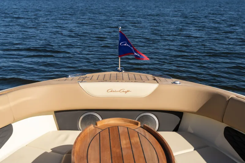 Slide: The Image of 2026 Chris-Craft Sportster 28 boat interior with wooden table and flag on open water. - 9