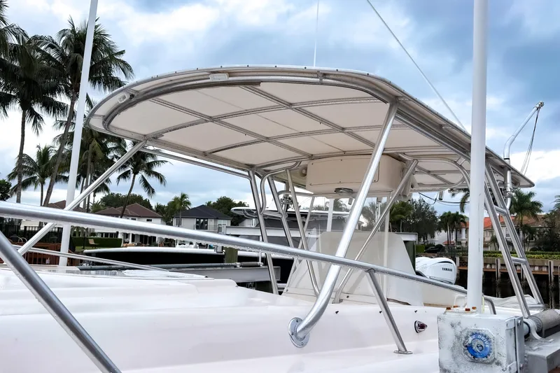 Slide: The Image of 1998 Intrepid 356 Cuddy boat with T-top, docked near palm trees and waterfront homes. - 31