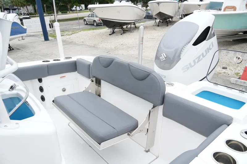 Slide: The Image of 2025 NauticStar 242 Offshore boat interior with Suzuki engine, featuring gray seating and storage compartments. - 21