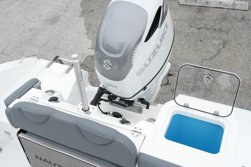Slide: The Image of 2025 NauticStar 242 Offshore boat with Suzuki engine and open storage compartment. - 23