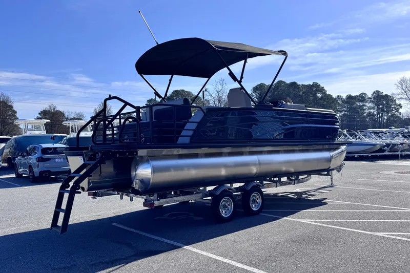 Slide: The Image of 2026 Sylvan L3 CLZ pontoon boat on trailer in parking lot, under clear blue sky. - 2