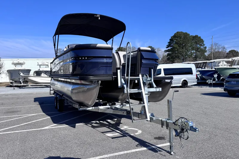 Slide: The Image of 2026 Sylvan L3 CLZ pontoon boat on trailer in parking lot, under clear blue sky. - 3
