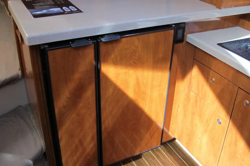 Slide: The Image of 2006 Cruisers Yachts 385 Motoryacht kitchen with wood cabinetry and compact refrigerator. - 29