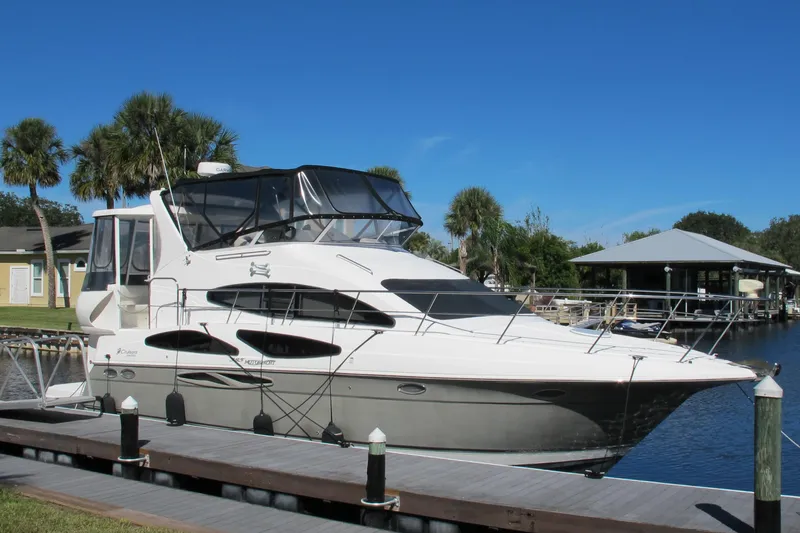 The Image of 2006 Cruisers Yachts 385 Motoryacht docked by palm trees and waterfront homes. - 1