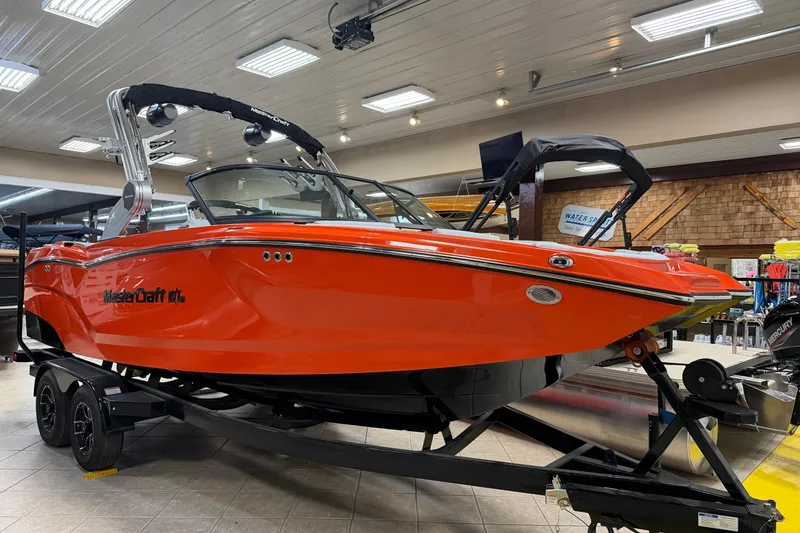 The Image of 2026 MasterCraft NXT22 boat in vibrant orange on display indoors. - 1