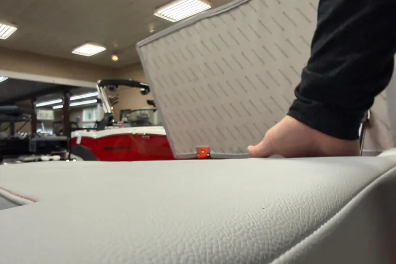 Slide: The Image of 2026 MasterCraft NXT22 boat interior with hand adjusting seat in showroom. - 15