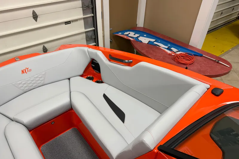 Slide: The Image of 2026 MasterCraft NXT22 boat interior with orange and gray seating in a garage setting. - 8