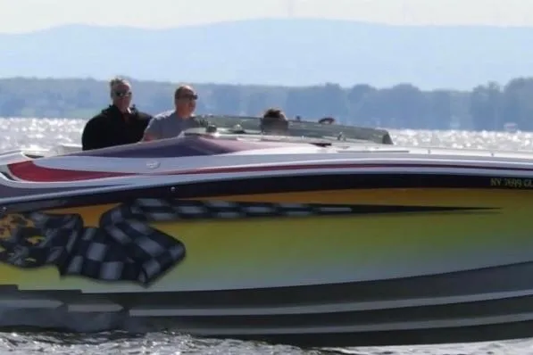 Slide: The Image of 2000 Hustler 388 SLINGSHOT speedboat on water with passengers, featuring vibrant graphics. - 3