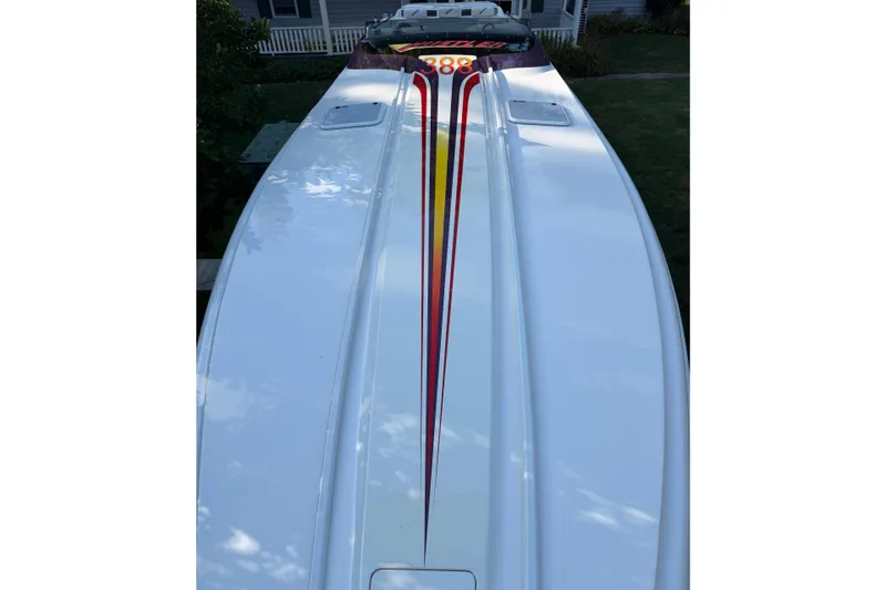 Slide: The Image of 2000 Hustler 388 SLINGSHOT boat with sleek design and vibrant stripes. - 6