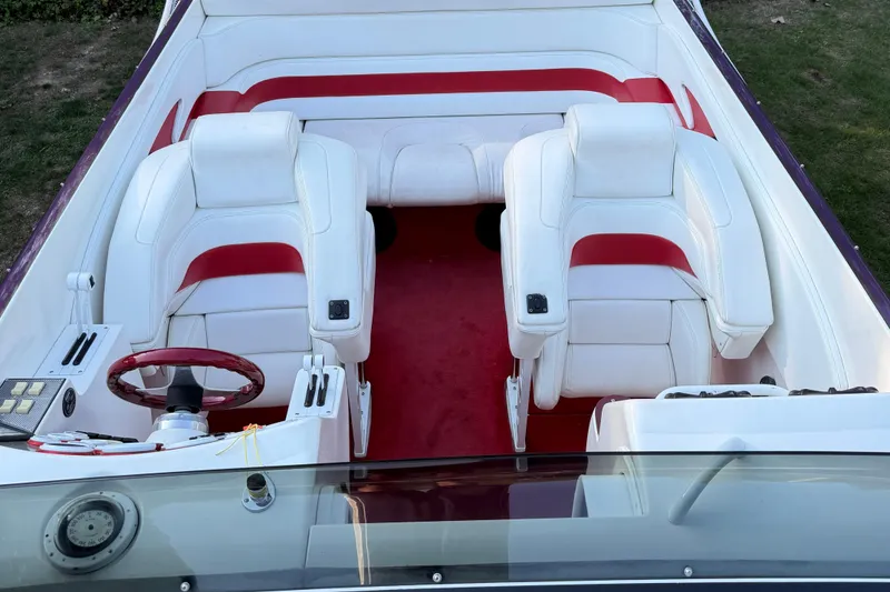 Slide: The Image of 2000 Hustler 388 SLINGSHOT boat interior with white and red seating, red carpet, and steering wheel. - 7